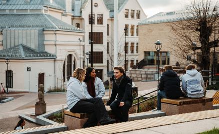 en gruppe mennesker som sitter på en benk foran en bygning