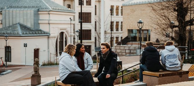 en gruppe mennesker som sitter på en benk foran en bygning