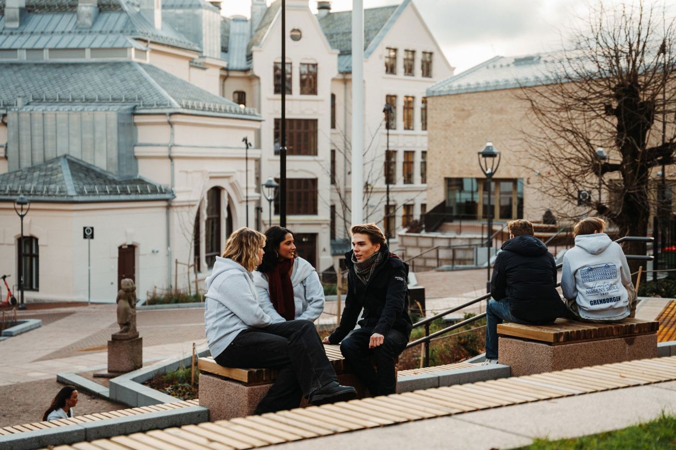 en gruppe mennesker som sitter på en benk foran en bygning