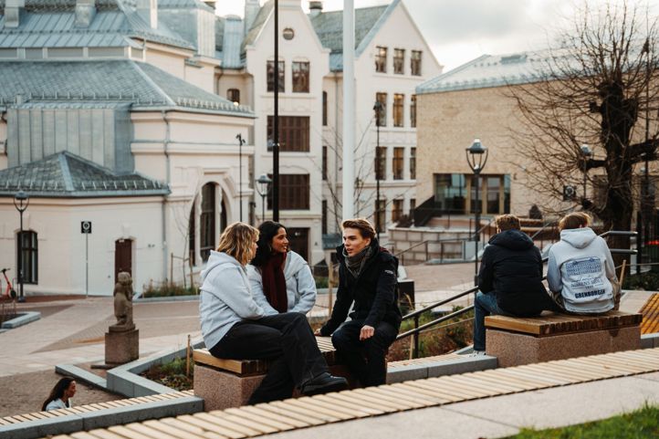 en gruppe mennesker som sitter på en benk foran en bygning