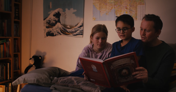 en gruppe mennesker som sitter i en sofa og leser bøker